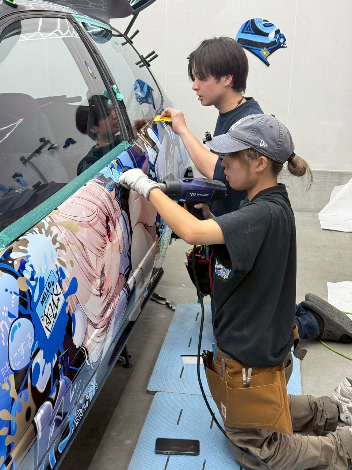 2人でドアにラッピングシートを貼る様子